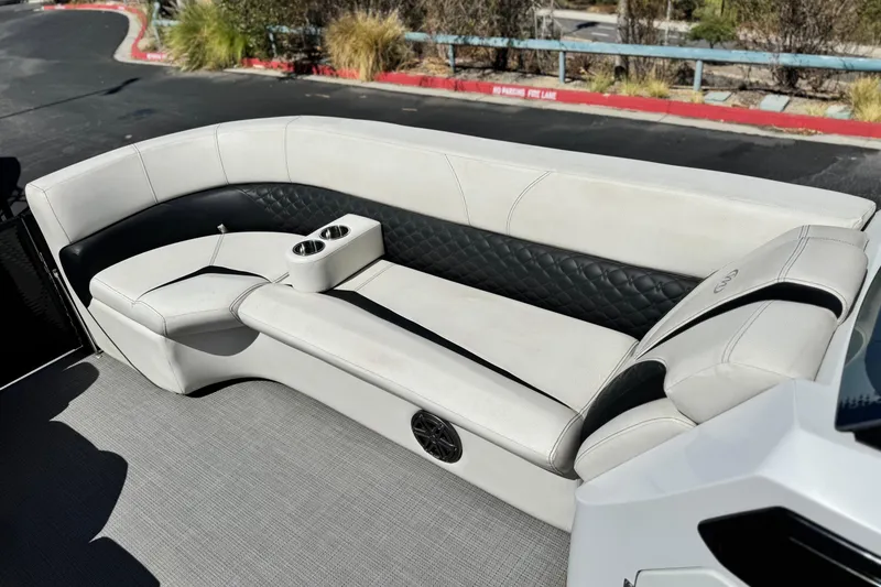 Slide: The Image of 2021 Manitou 25 LX SHP boat interior with white and black seating and cup holders. - 11