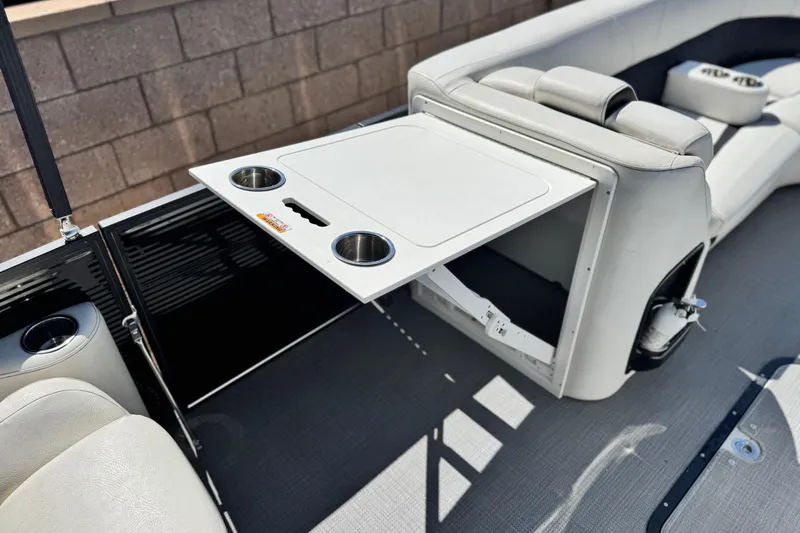 Slide: The Image of 2021 Manitou 25 LX SHP boat interior with fold-out table and cup holders. - 14