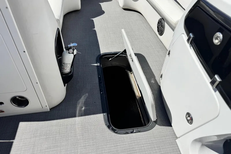 Slide: The Image of 2021 Manitou 25 LX SHP boat interior with open storage compartment and fire extinguisher. - 16