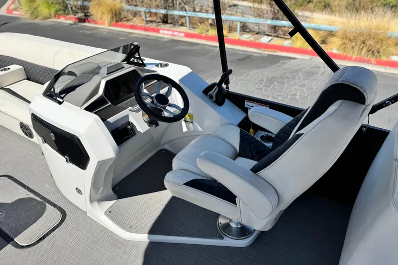 Slide: The Image of 2021 Manitou 25 LX SHP boat interior with steering wheel and captain's chair. - 22