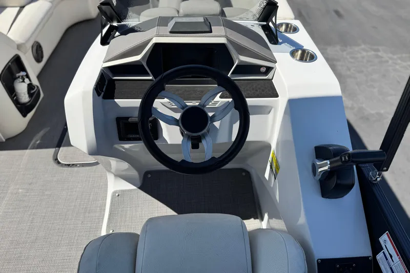 Slide: The Image of 2021 Manitou 25 LX SHP boat helm with modern steering wheel and controls. - 23