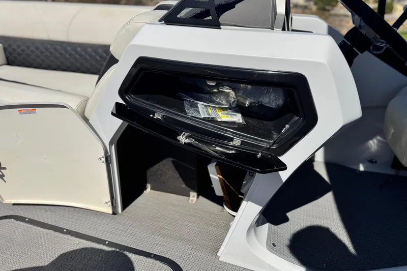 Slide: The Image of 2021 Manitou 25 LX SHP boat interior with open storage compartment and seating. - 26