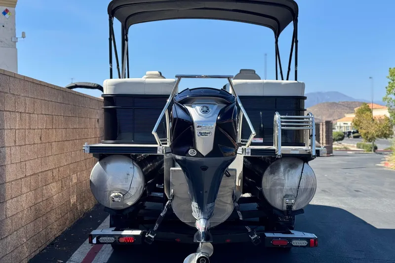 Slide: The Image of 2021 Manitou 25 LX SHP pontoon boat with outboard motor, parked on a trailer. - 5