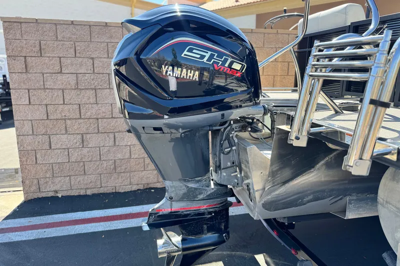 Slide: The Image of 2021 Manitou 25 LX SHP with Yamaha VMAX outboard motor, parked near a brick wall. - 7