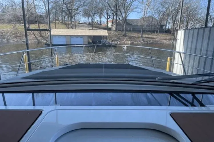 Slide: The Image of 2018 Cruisers Yachts 390 Express Coupe docked near a boathouse on a calm lake. - 13