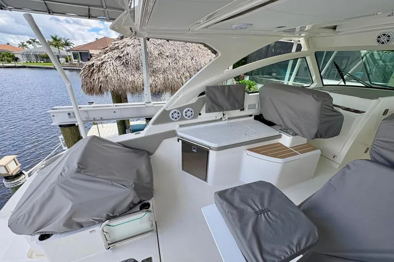 Slide: The Image of 2024 Tiara Yachts 34 LX interior with covered seating and modern amenities by the water. - 11