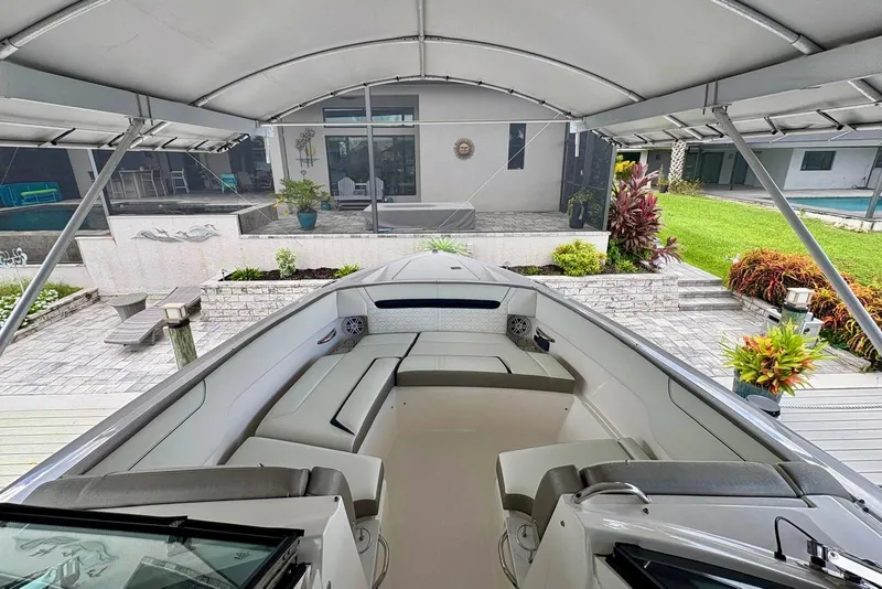 Slide: The Image of 2024 Tiara Yachts 34 LX boat under canopy, docked near modern home with garden. - 18