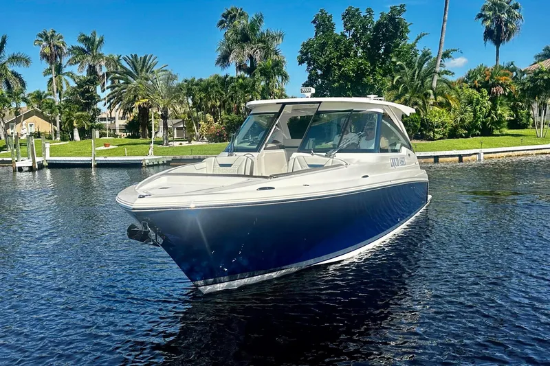 Slide: The Image of 2024 Tiara Yachts 34 LX boat on a sunny day, surrounded by lush greenery. - 22