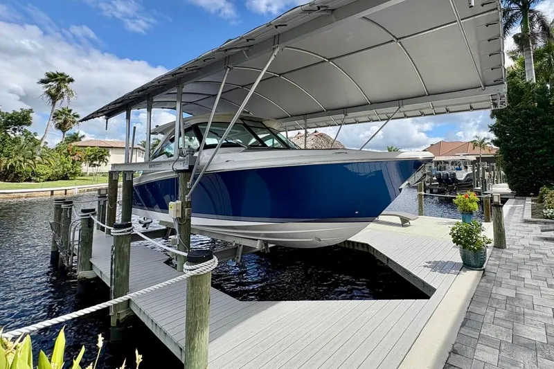 Slide: The Image of 2024 Tiara Yachts 34 LX on dock, covered, with lush surroundings and water view. - 3