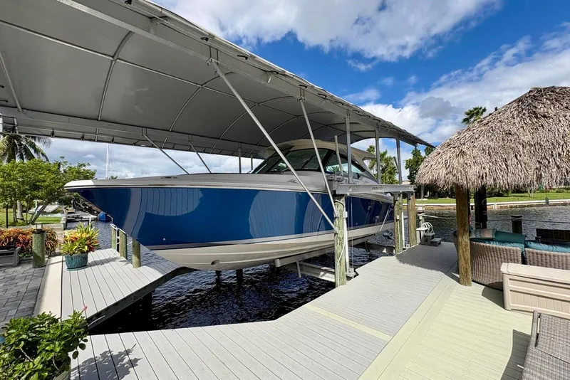 Slide: The Image of 2024 Tiara Yachts 34 LX on a covered dock, surrounded by tropical scenery. - 4