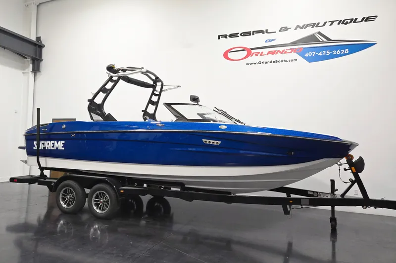 The Image of 2026 Supreme S220 boat in showroom, blue exterior, on trailer, Orlando dealership. - 1