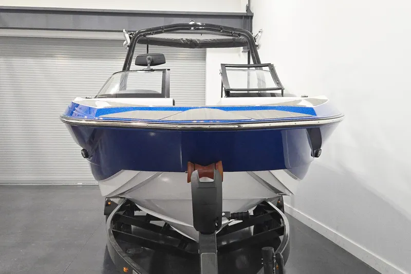 Slide: The Image of 2026 Supreme S220 boat in showroom, blue and white design, on trailer. - 2