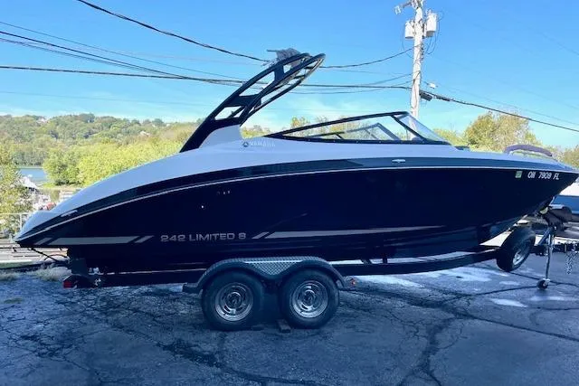 The Image of 2015 Yamaha Boats 242 Limited S on trailer, sleek black design, parked outdoors. - 1
