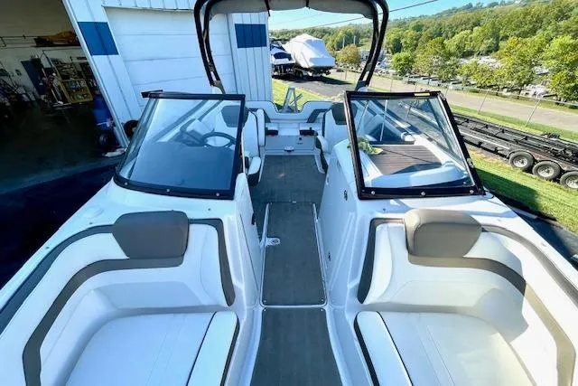 Slide: The Image of 2015 Yamaha Boats 242 Limited S interior with seating and windshield, docked outdoors. - 18
