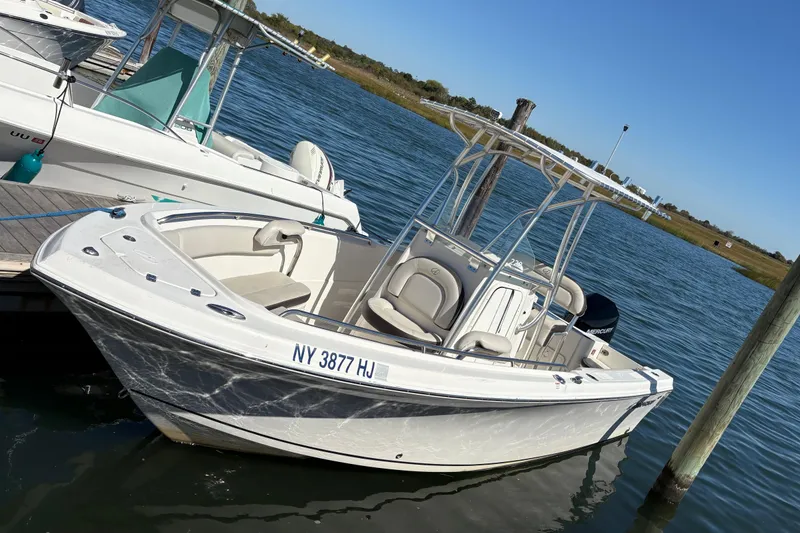 The Image of 2023 Sailfish 220CC boat docked on calm water under clear blue sky. - 1