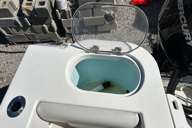 Slide: The Image of 2023 Sailfish 220CC boat livewell with open lid, showing interior and nearby Mercury engine. - 11