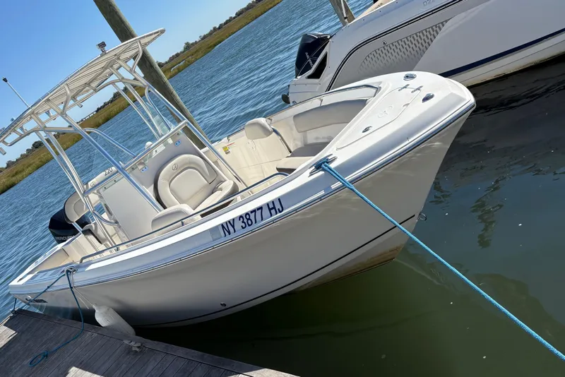 Slide: The Image of 2023 Sailfish 220CC boat docked on calm water, clear sky background. - 3