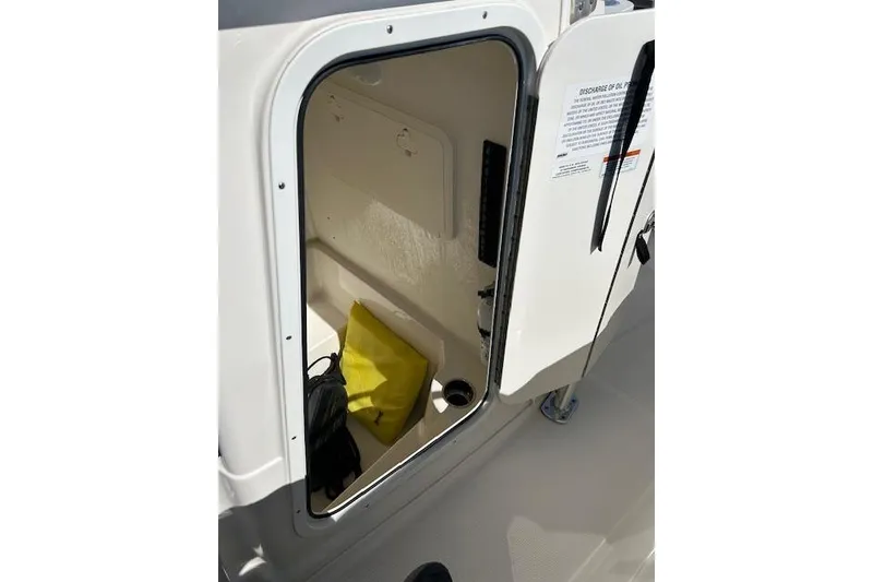 Slide: The Image of Open storage compartment on 2023 Sailfish 220CC boat, featuring interior space and safety gear. - 8