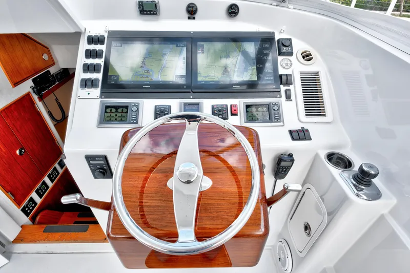 Slide: The Image of Boat helm with dual navigation screens, wooden steering wheel, and control panel, Release Walkaround 2014. - 28