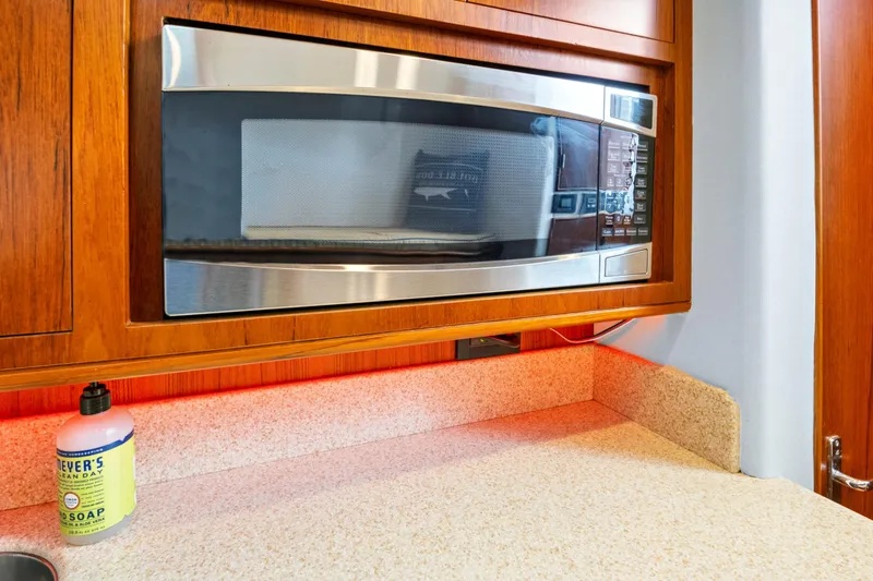 Slide: The Image of Built-in microwave in wooden cabinet, beige countertop, and soap bottle. - 42