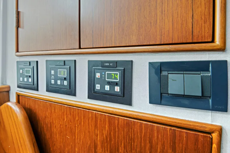 Slide: The Image of Control panels on a 2014 Release Walkaround boat, featuring AC and switch controls. - 53