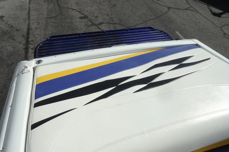 Slide: The Image of 1998 Baja 29 Outlaw boat with colorful deck design featuring blue, yellow, and black accents. - 23