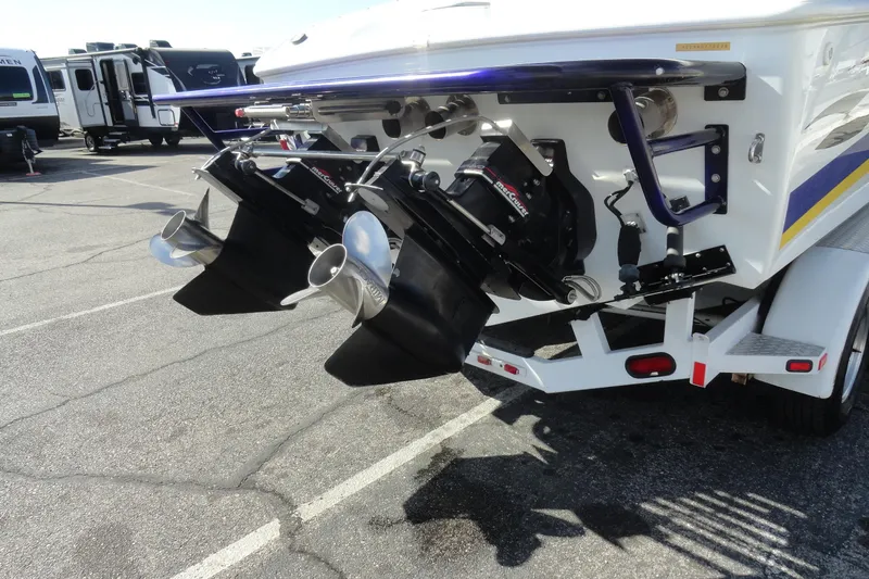 Slide: The Image of 1998 Baja 29 Outlaw boat with dual propellers on a trailer in a parking lot. - 27