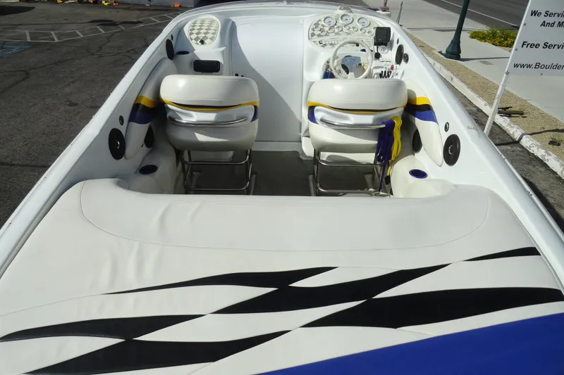 Slide: The Image of 1998 Baja 29 Outlaw boat interior with white seating and dashboard, parked on pavement. - 7