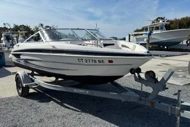 The Image of 2009 Glastron GT 185 boat on trailer, parked outdoors under clear sky. - 0