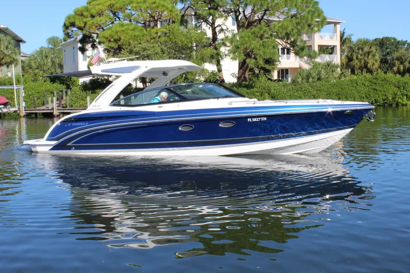 Slide: The Image of 2023 Formula 330 Crossover Bowrider on calm water, surrounded by lush greenery. - 10