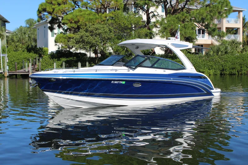 Slide: The Image of 2023 Formula 330 Crossover Bowrider on calm water, surrounded by lush greenery. - 2
