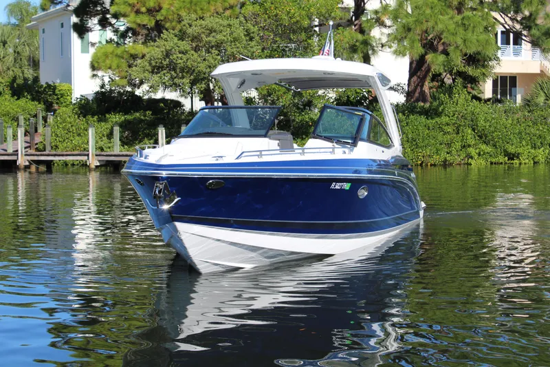 Slide: The Image of 2023 Formula 330 Crossover Bowrider on calm water, surrounded by lush greenery. - 7