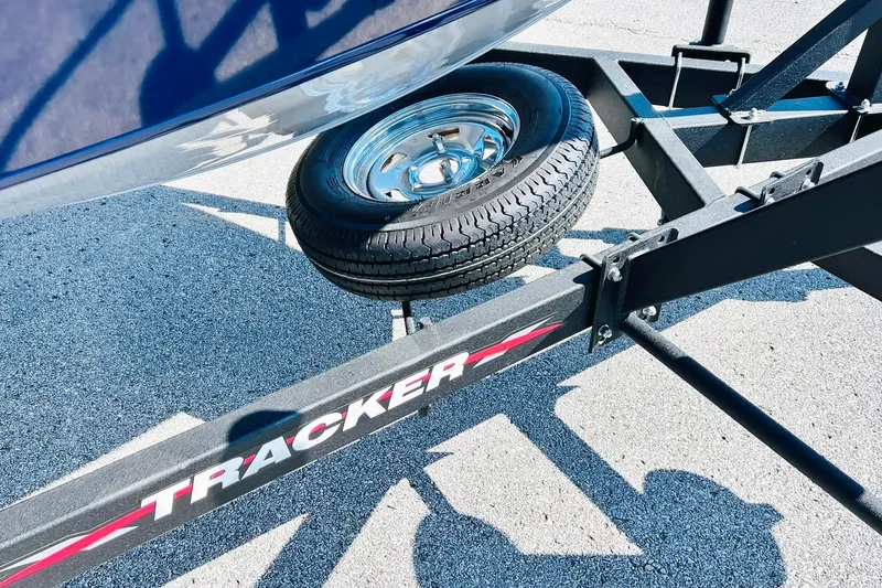 Slide: The Image of 2024 Tracker Targa V-18 Combo trailer with spare tire on asphalt. - 32