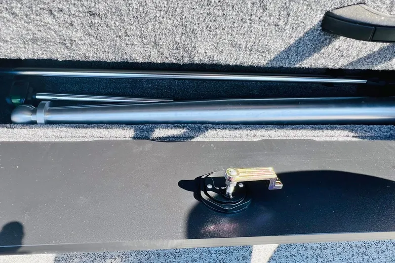 Slide: The Image of 2024 Tracker Targa V-18 Combo storage compartment with metal rods and latch mechanism. - 35