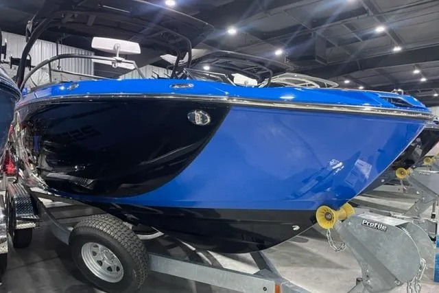 Slide: The Image of 2024 Yamaha Boats 255XD in blue and black on a trailer in a showroom. - 1