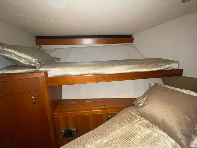 Slide: The Image of 2013 Hatteras GT63 cabin with wooden bunk beds and beige bedding. - 10