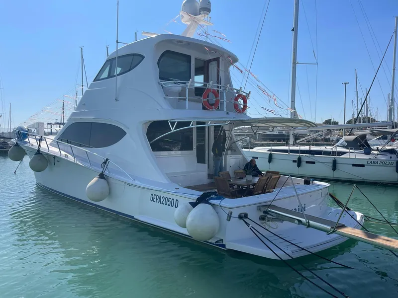 Slide: The Image of 2013 Hatteras GT63 yacht docked in marina, featuring sleek design and spacious deck. - 2