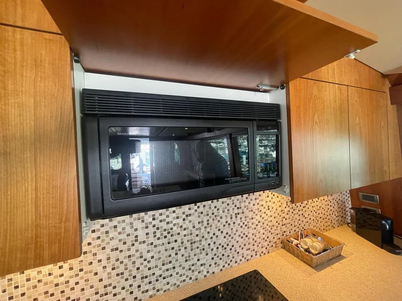 Slide: The Image of Modern kitchen interior of 2013 Hatteras GT63 yacht with microwave and wooden cabinets. - 36