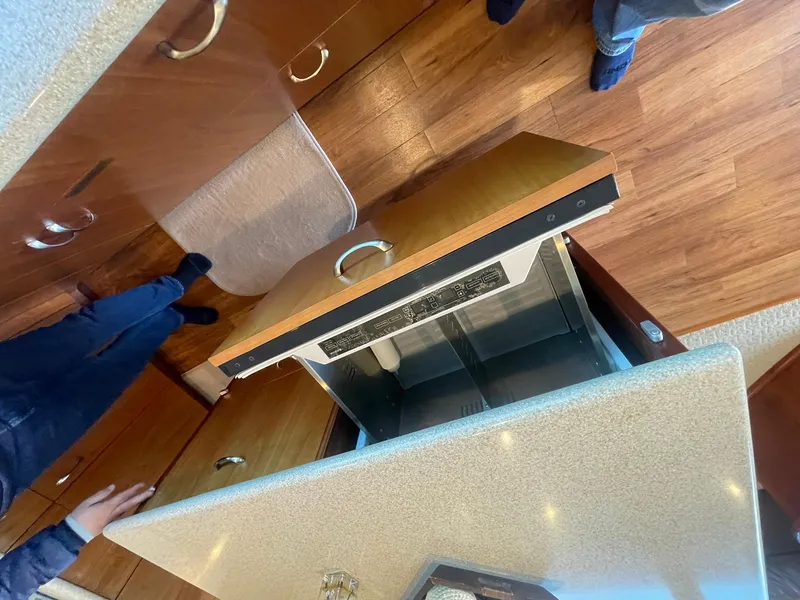 Slide: The Image of Interior of 2013 Hatteras GT63 yacht showing open dishwasher and wooden flooring. - 40