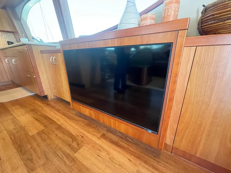 Slide: The Image of 2013 Hatteras GT63 yacht interior with built-in TV, wooden cabinetry, and decorative items. - 41