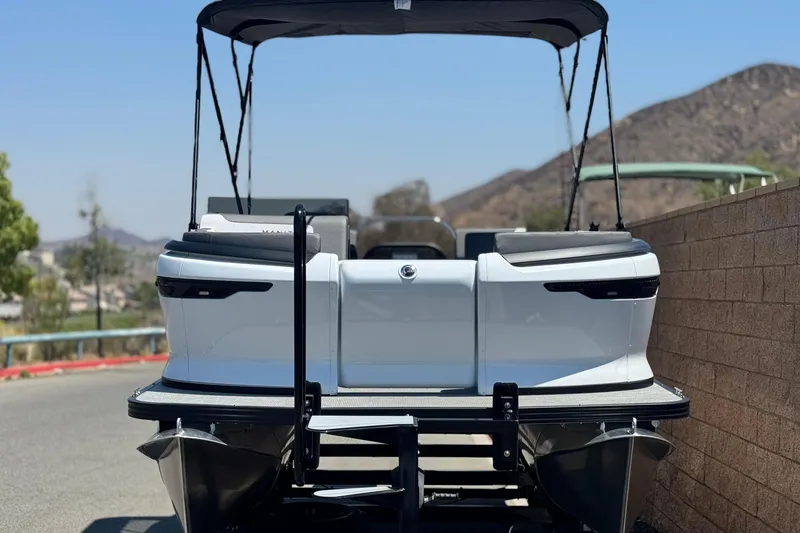 Slide: The Image of 2025 Manitou Cruise 20 pontoon boat, rear view, parked on a sunny day. - 2