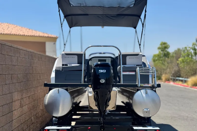 Slide: The Image of 2025 Manitou Cruise 20 pontoon boat with 90 HP engine, parked outdoors. - 4