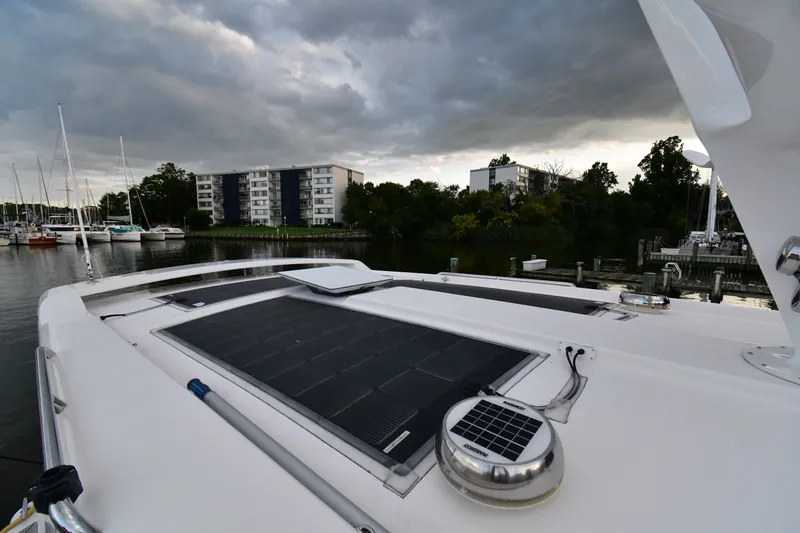 Slide: The Image of 2021 Hylas M44 yacht with solar panels, docked near waterfront buildings under cloudy skies. - 23