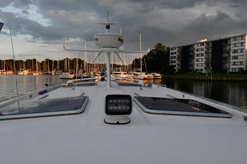 Slide: The Image of Bow view of 2021 Hylas M44 yacht in marina, with cloudy sky and waterfront buildings. - 24