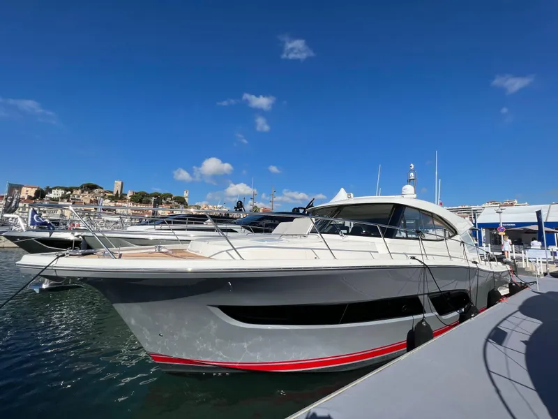 The Image of 2022 Riviera 505 SUV yacht docked in a marina under clear blue skies. - 0