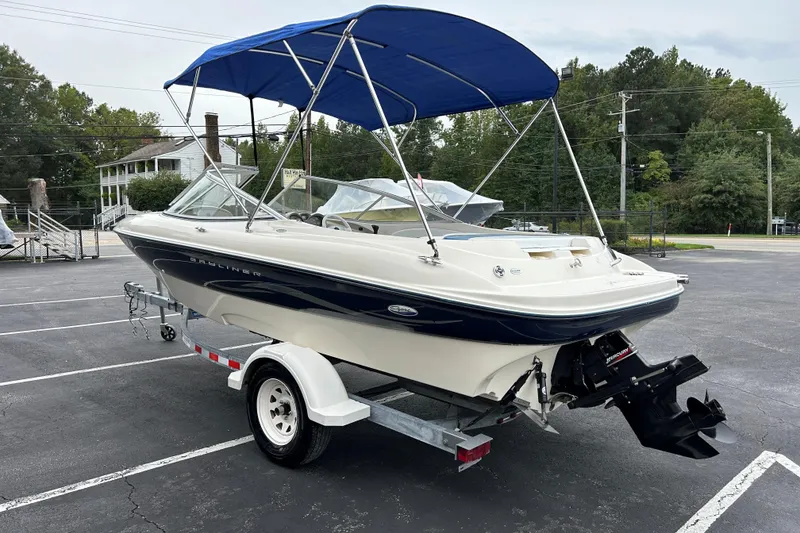 Slide: The Image of 2002 Bayliner 195 Capri boat with blue canopy on a trailer in a parking lot. - 4
