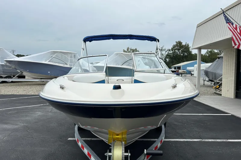 Slide: The Image of 2002 Bayliner 195 Capri boat on trailer, parked outdoors near other boats. - 9