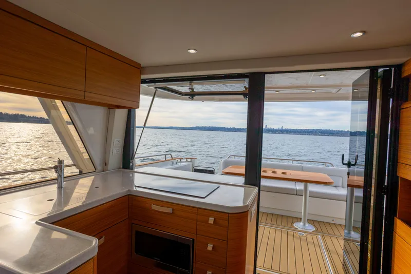 Slide: The Image of Interior view of 2023 Greenline 48 Fly yacht with modern kitchen and scenic ocean backdrop. - 2