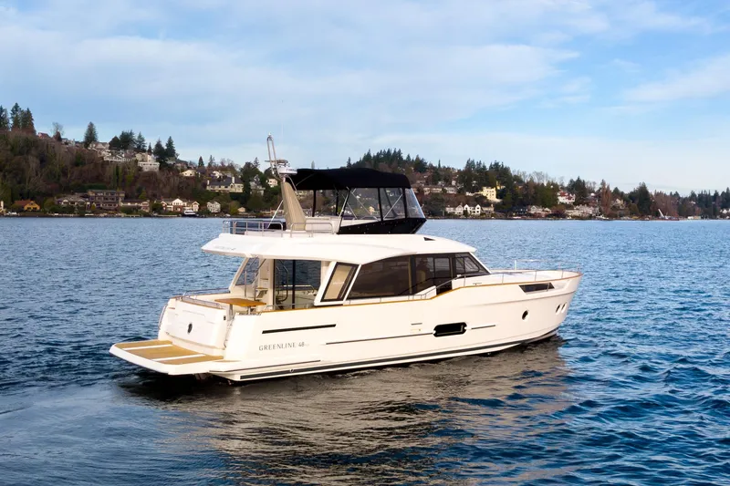 Slide: The Image of 2023 Greenline 48 Fly yacht cruising on a scenic lake with hillside homes. - 27