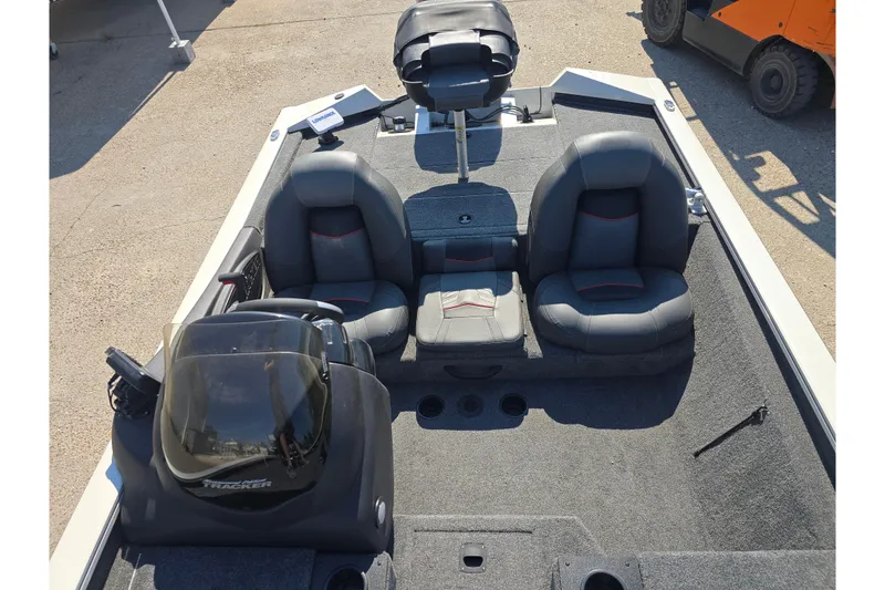 Slide: The Image of 2024 Tracker Pro Team 190 TX boat interior with seating and console, parked on concrete. - 11
